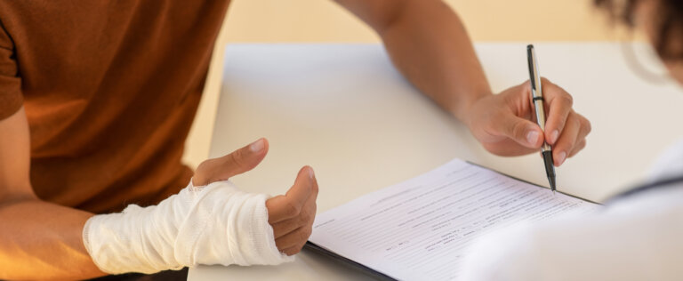 Man with broken arm filling health insurance claim form. Accident insurance disability compensation